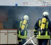 Zwei Feuerwehrmänner löschen Brand in Schutzkleidung