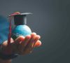 Kleine Weltkugel in einer Hand mit einem College-Hut drauf als Symbol für eine internationale Weiterbildung - nicht nur im Einkauf