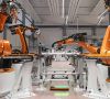 Mehrere orangene Kuka-Roboter arbeiten in einem Werk.