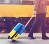 Person am Bahnsteig rollte einen Koffer in Ukraine-Farben hinter sich her