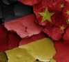 Flaggen von Deutschland und China auf einer rissigen Wand gemalt