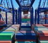 Luftaufnahme eines farbenfrohen Containerhafens und Logistikterminals im Kranbereich beim Be- und Entladen eines Containertankschiffs