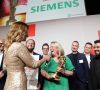 Das Bild zeigt das Sieger-Werk von Siemens zusammen mit Moderatorin Katrin Müller-Hohenstein.