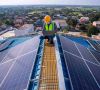Arbeiter auf einem mit Solarpaneelen bedeckten Dach