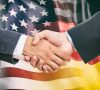 Händeschütteln vor Flaggen der USA und Deutschlands