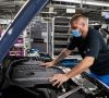 Ein BMW-Mitarbeiter, der Maske trägt, überprüft in einem Werk ein Auto.