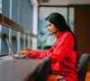 Eine junge indische Frau arbeitet an einem Laptop