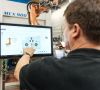 Ein Kuka-Mitarbeiter bedient einen Roboter über ein Display