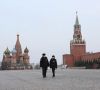 Zwei Menschen mit Maske laufen in Moskau eine Straße entlang