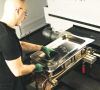 Mann mit grünen Handschuhen arbeitet an einer 3D-Laserschneidanlage