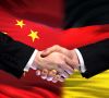 Chinesische und deutsche Flagge nebeneinander. Händeschütteln davor.