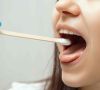 Ein Teststäbchen wird in den Mund einer Frau eingeführt.