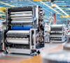 Blick in die Montagehalle von Heidelberger Druckmaschinen: Mehrere Mitarbeiter arbeiten an offenen Druckmaschinen